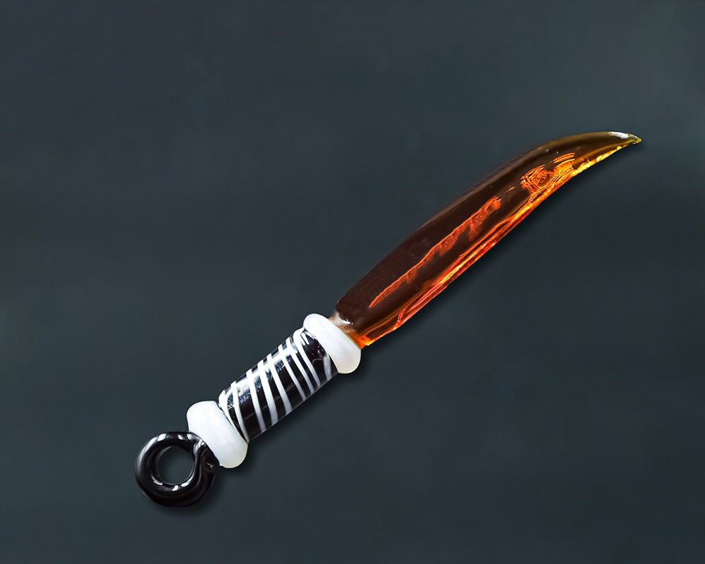 Curved amber glass blade dab tool with decorative black and white handle for flavor